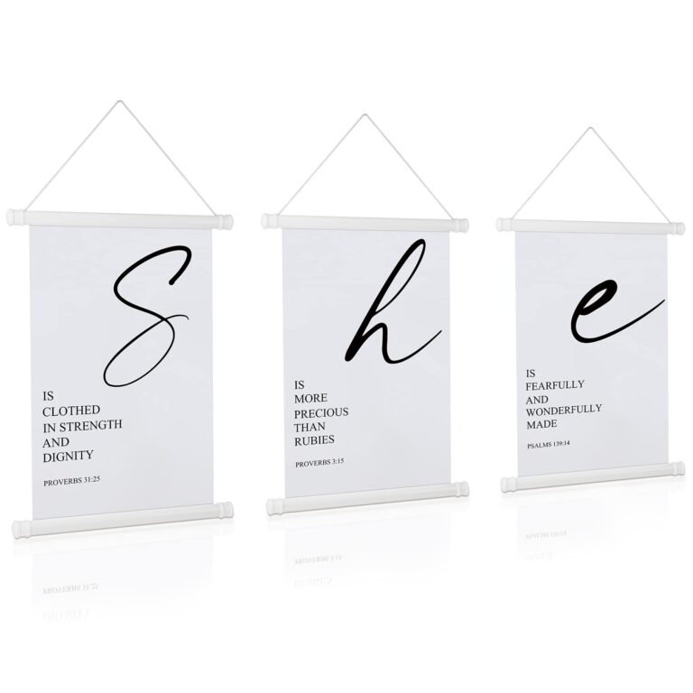 Three white wall hangings with "She" in large script and Bible verses